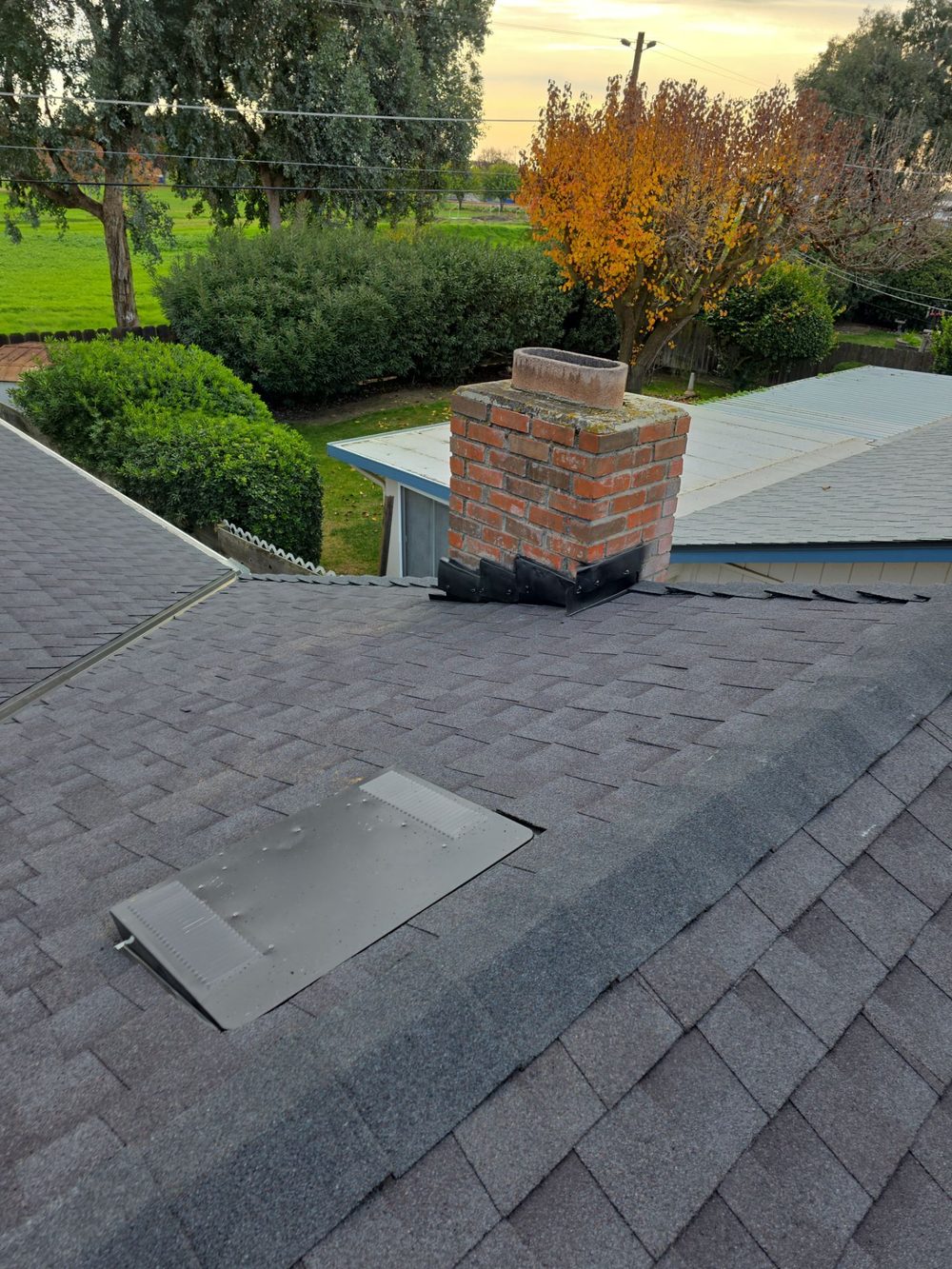 Completed brick chimney with new step flashing and counterflashing after Atwater residential roof replacement