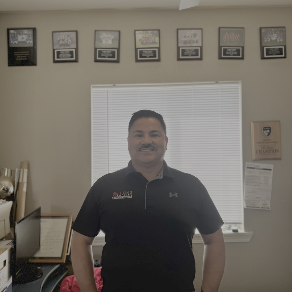 Mario Espindola, founder of Econo Roofing, in front of the company's certification wall