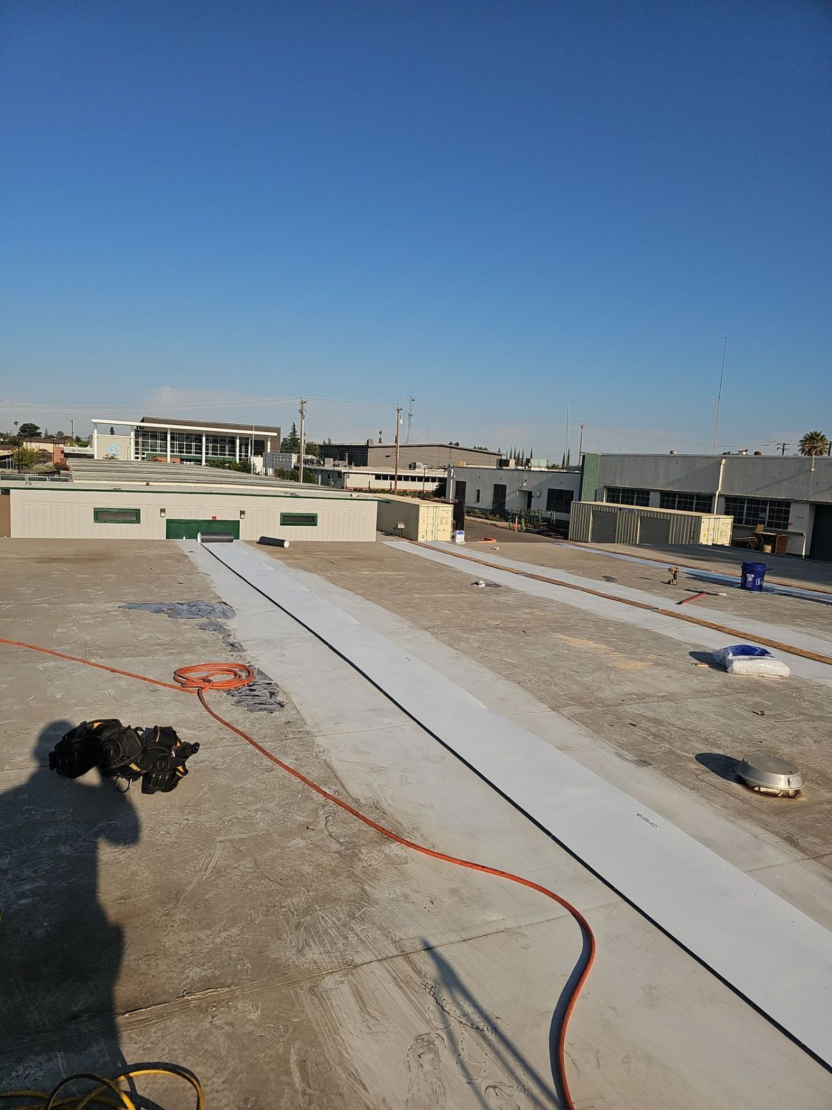 Parallel TPO membrane strips being laid on the Manteca High School roof