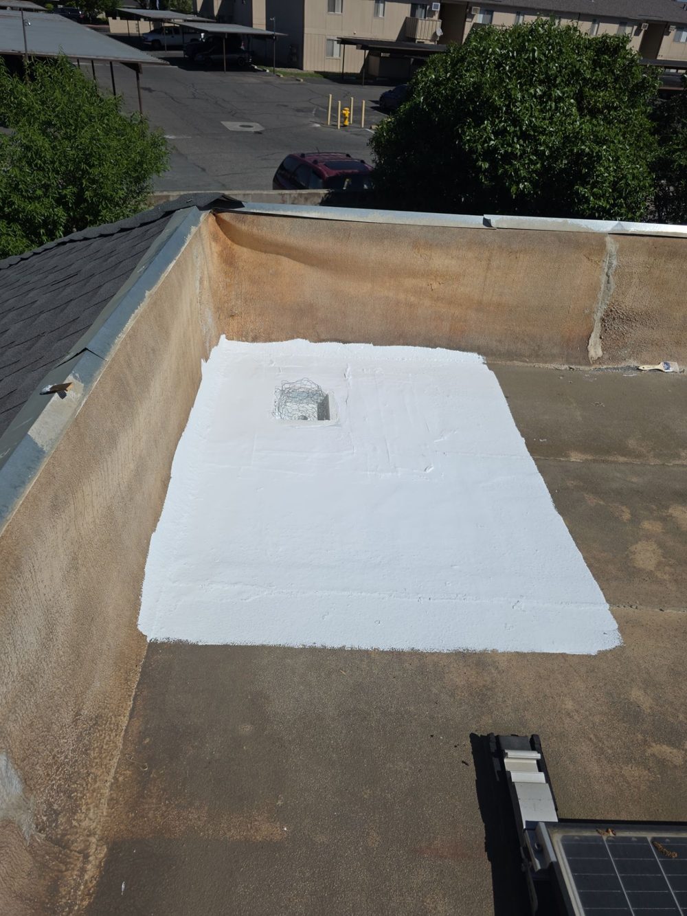 Completed white waterproofing patch around the repaired roof drain in Modesto