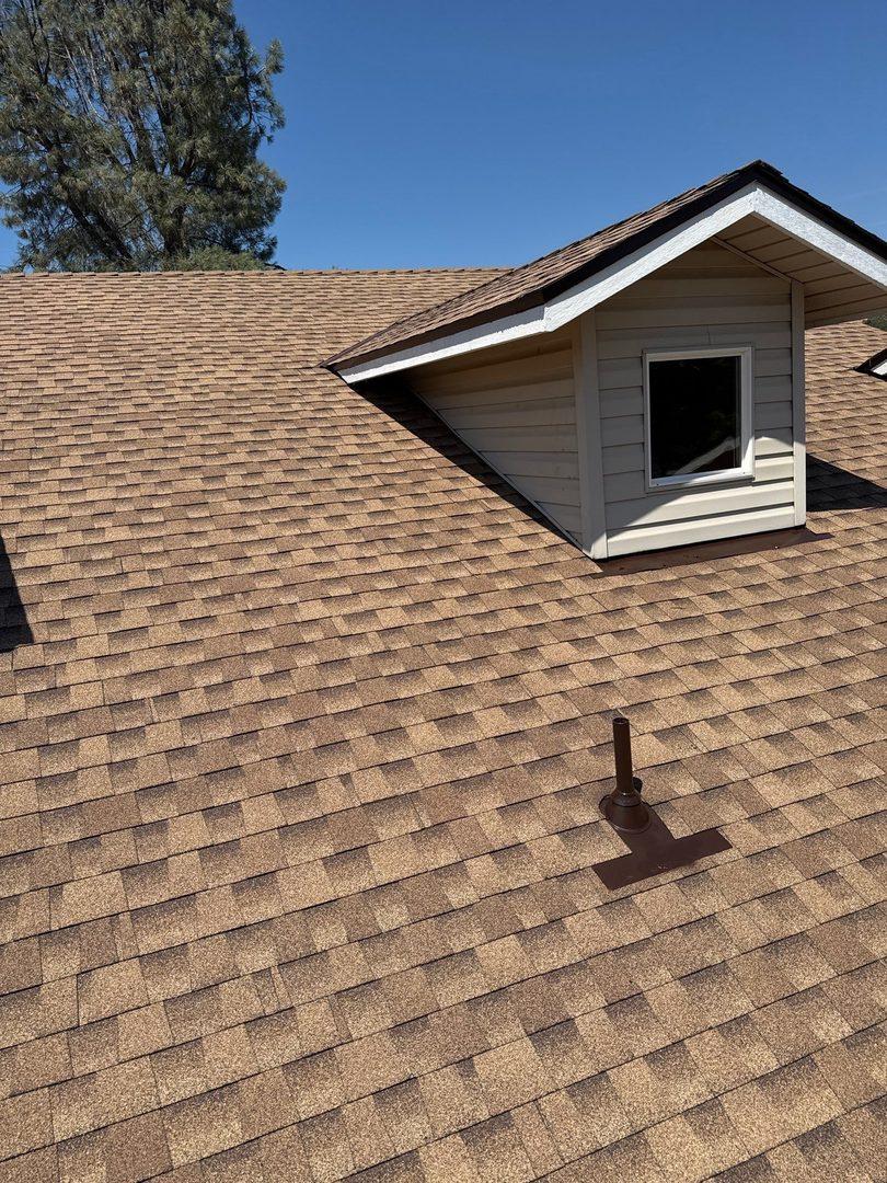 New shingles on dormer with clean white trim against blue sky