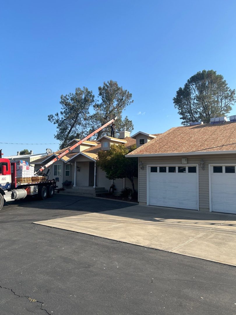 Boom truck delivering shingle bundles to roof of lakefront home