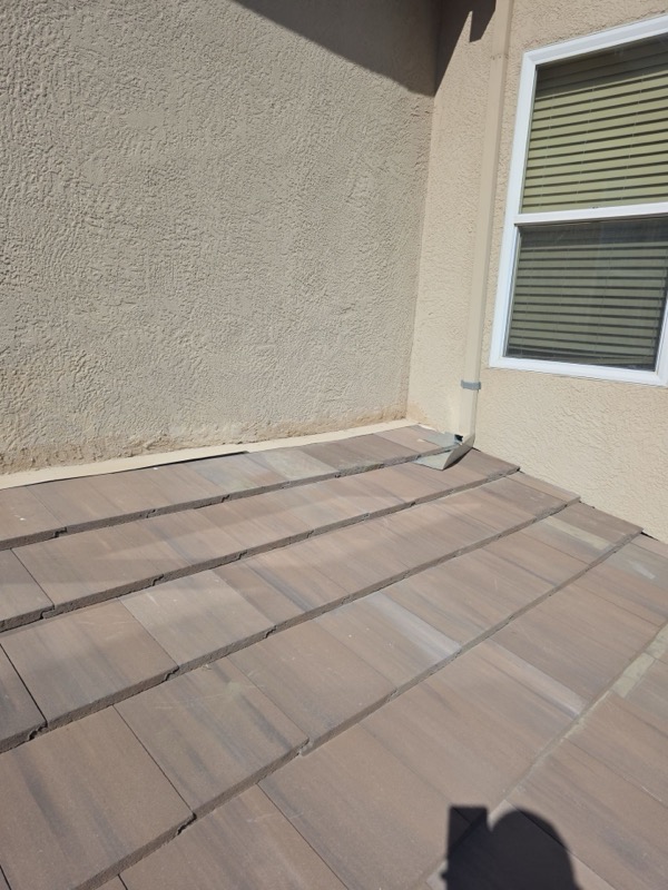 Completed tile roof leak repair with new flashing at wall junction