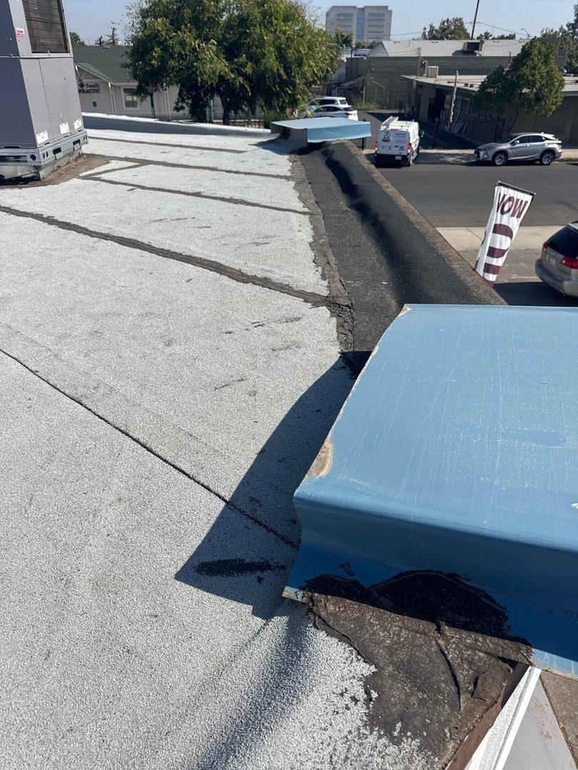 Wide view of degraded commercial roof edge with failing flashing and HVAC units