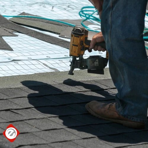 Econo Roofing crew member installing shingles with a pneumatic nail gun on a Central Valley residential roof — close-up action shot with branded Econo Roofing icon visible in the corner.